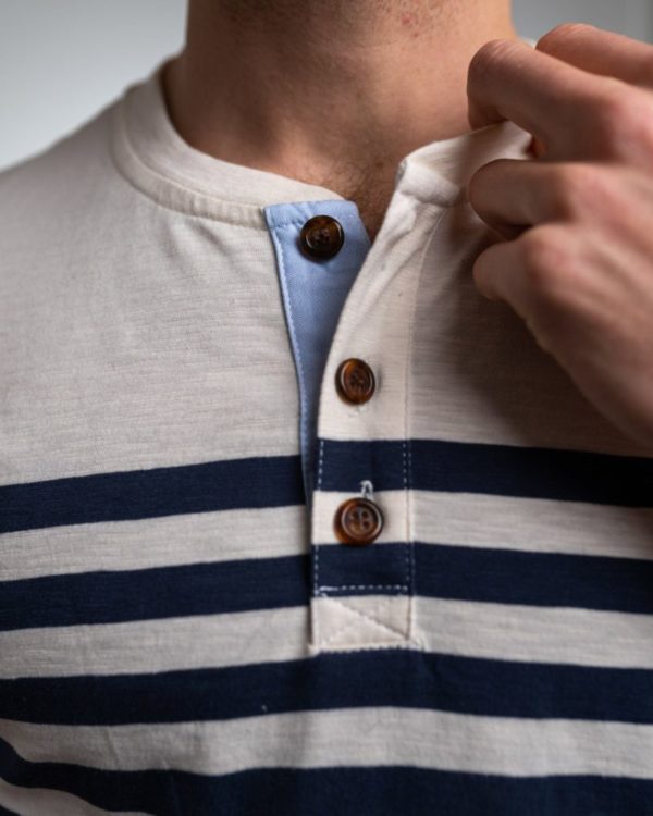 Détail du col boutonné du t shirt homme avec l'intérieur de la patte de boutonnage contrasté de bleu ciel et boutons corne
