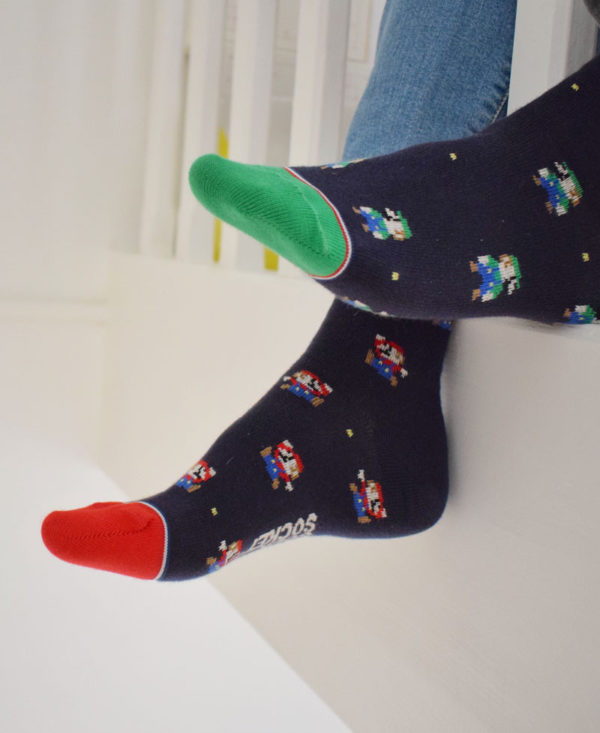 Photo des chaussettes dépareillées portées montrant la différence entre les deux pieds : une pointe rouge, bonhomme MARIO, une pointe verte bonhomme LUIGI
