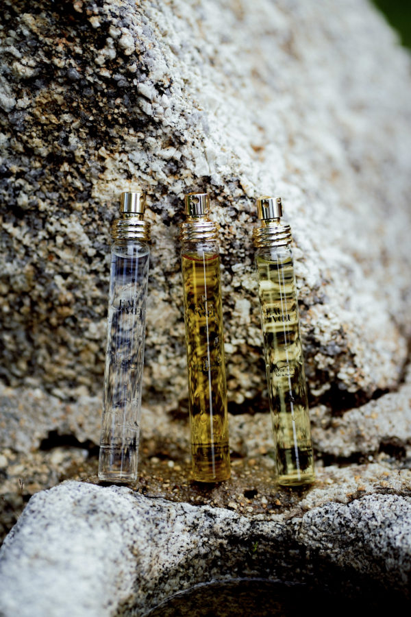 Trois flacon d'eau de parfum "EAU DE VOEU" alignés sur une pierre en granit
