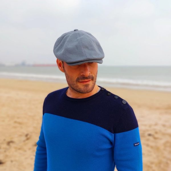 casquette plate en coton lin gris bleuté portée par un mannequin homme en bord de plage