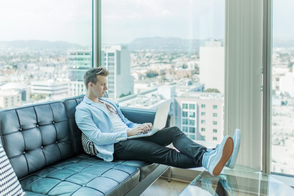 homme jambes allongées devant son pc portable