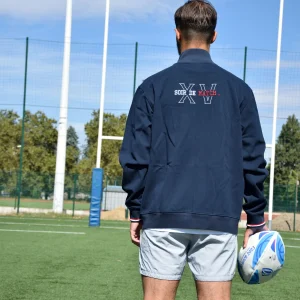Photo de la veste sippée DIMITRI de dos portée sur un short sur un terrain de rugby face aux poteaux