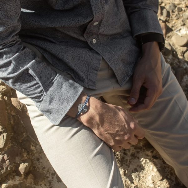 photo porté du bracelet LABECH par un homme en chemise assis dans des rochers