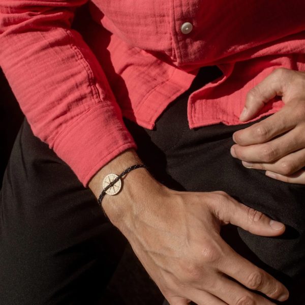 Photo porté cadré serré du bracelet bois l'épine par un homme en chemise framboise et pantalon noir